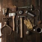 clothes iron, hammer, axe, flashlight and pitcher on brown wooden table