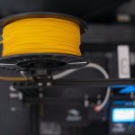 a spool of yellow wire sitting on top of a machine