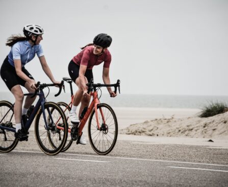 man and woman riding road bikes at the road near shore