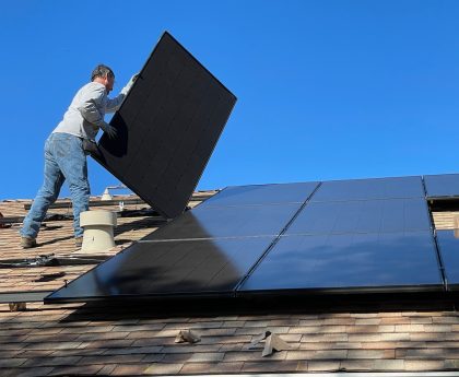 man in white dress shirt and blue denim jeans sitting on white and black solar panel